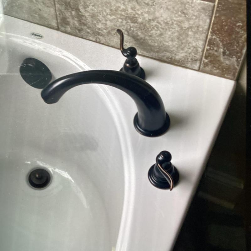 Tub faucet with black handles on white surround Tub faucet with black handles on white surround