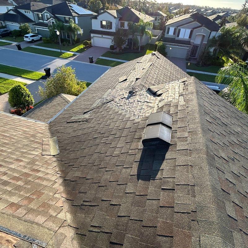 Storm-damaged asphalt roof shingles in suburban neighborhood Storm-damaged asphalt roof shingles in suburban neighborhood