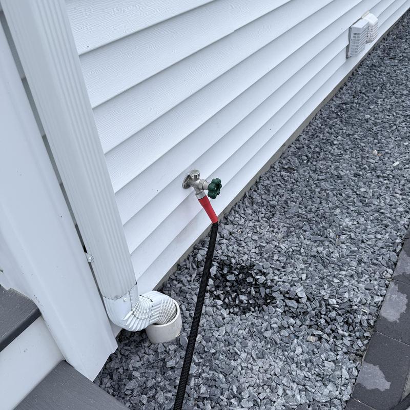 Silcock with hose connection on house exterior gravel bed