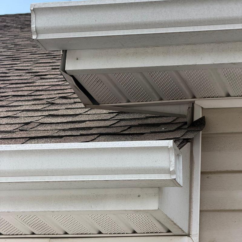 Roof shingles and gutter with edge damage and misalignment