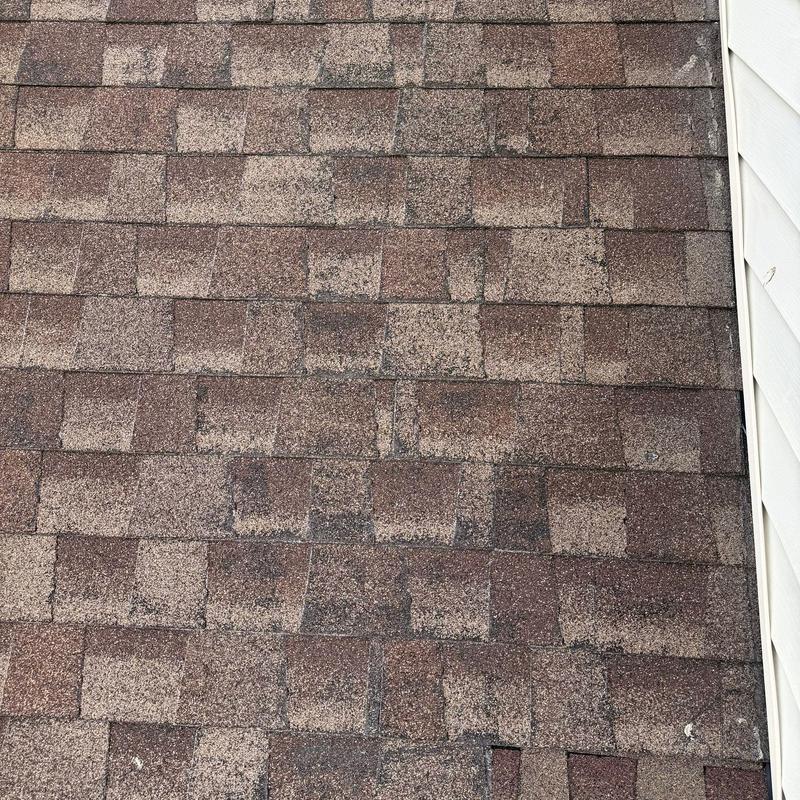Roof shingles with hail damage and wear near siding