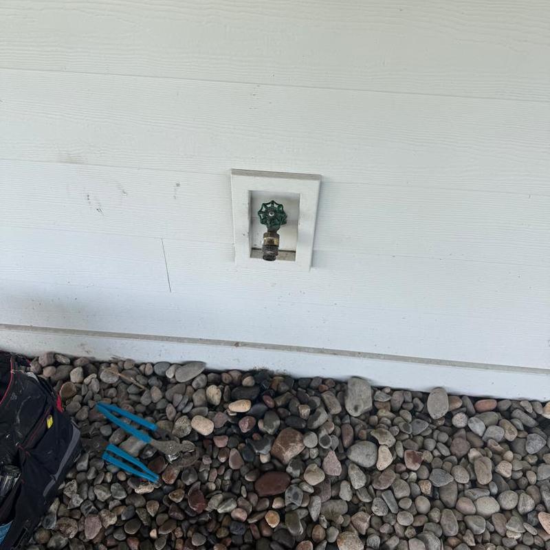 Outdoor water spigot with tools on rocky ground