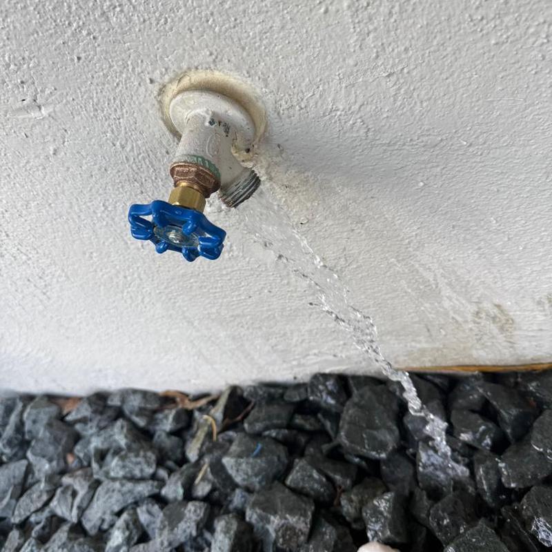 Outdoor water spigot leaking water onto ground stones