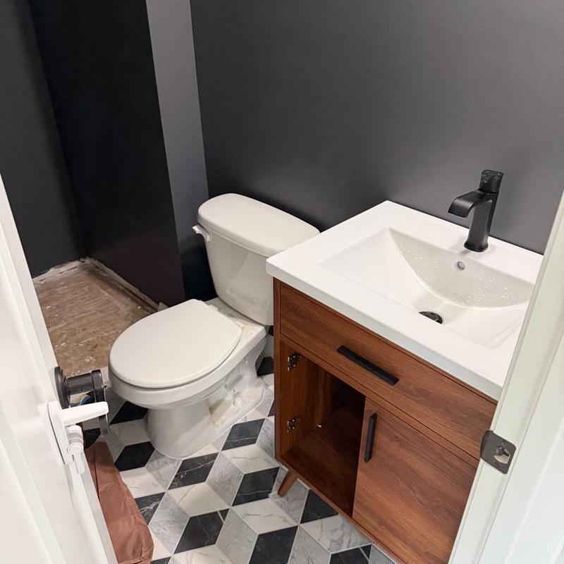 Bathroom sink and toilet with wood vanity in remodel