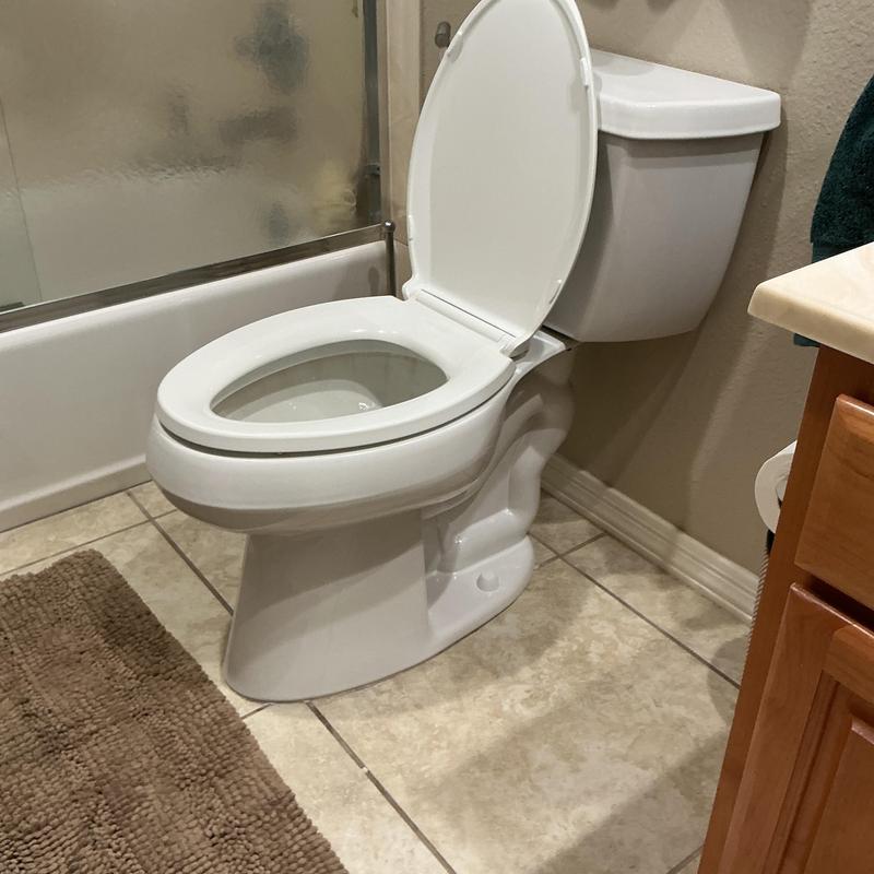 Toilet with raised seat and open lid in bathroom