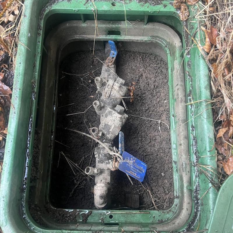 Backflow preventer valve in valve box with soil debris Backflow preventer valve in valve box with soil debris