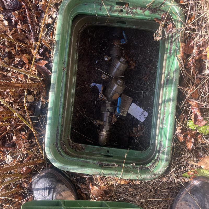 Backflow preventer inside green valve box outdoors Backflow preventer inside green valve box outdoors