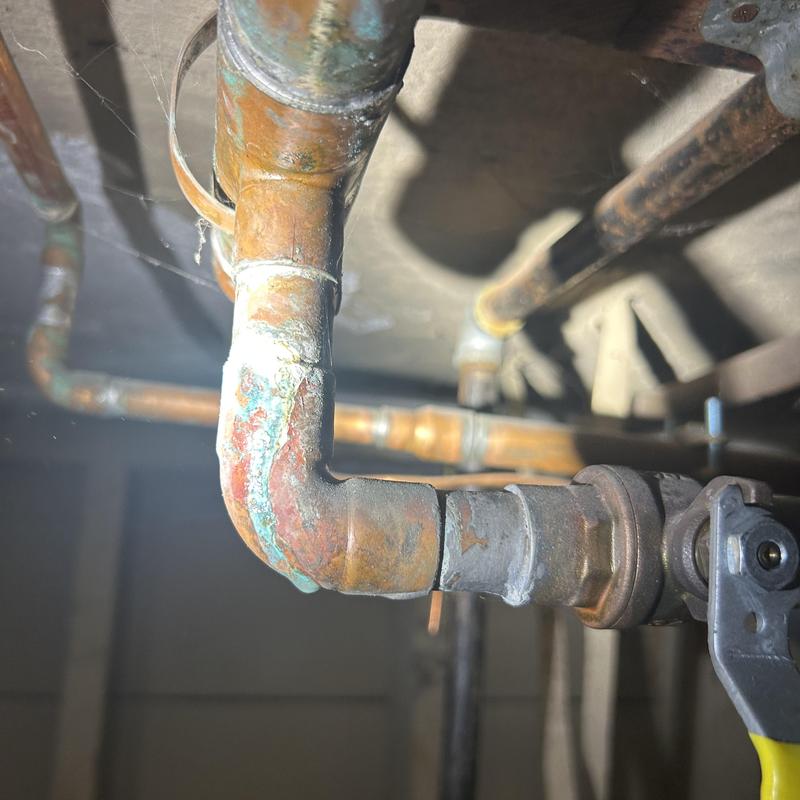 Corroded copper pipe elbow with valve under sink