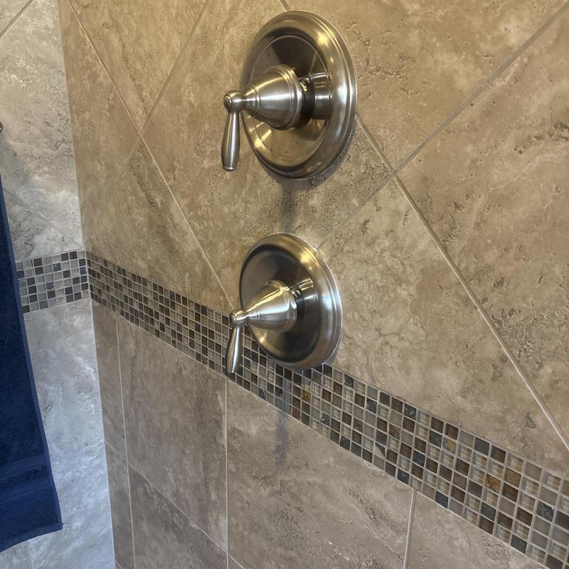 Moen Posi-Temp shower valve handles on tiled wall