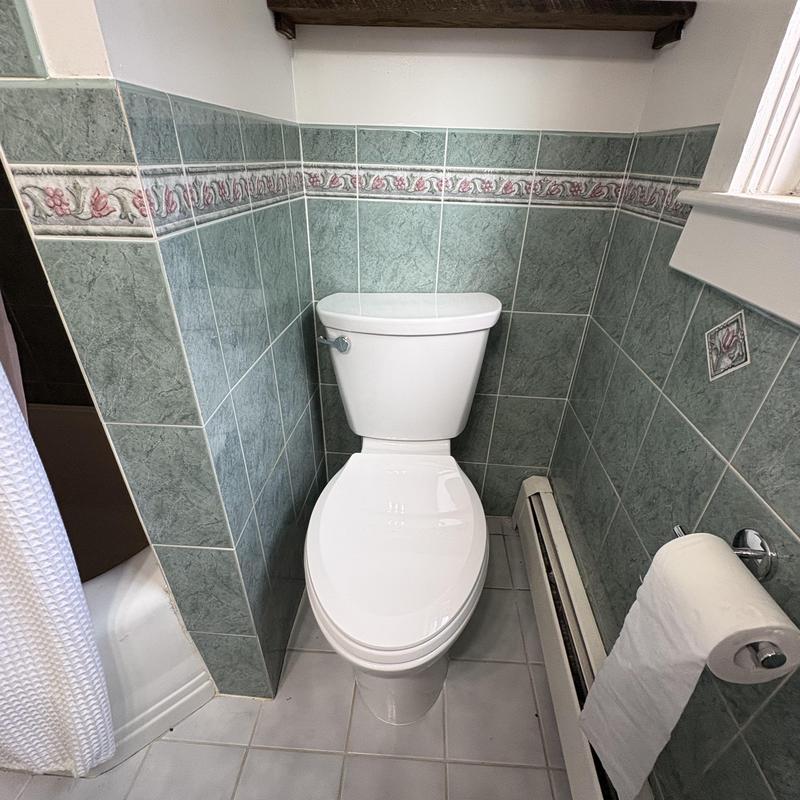 American Standard toilet installed in tiled bathroom corner