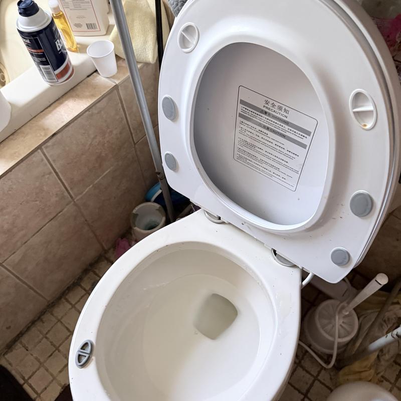 Toilet bowl with open lid in bathroom setting