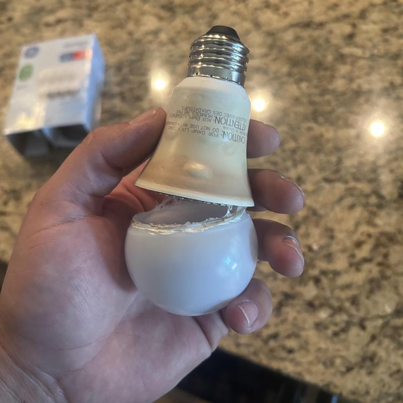 Light bulb broken in half held by hand on countertop