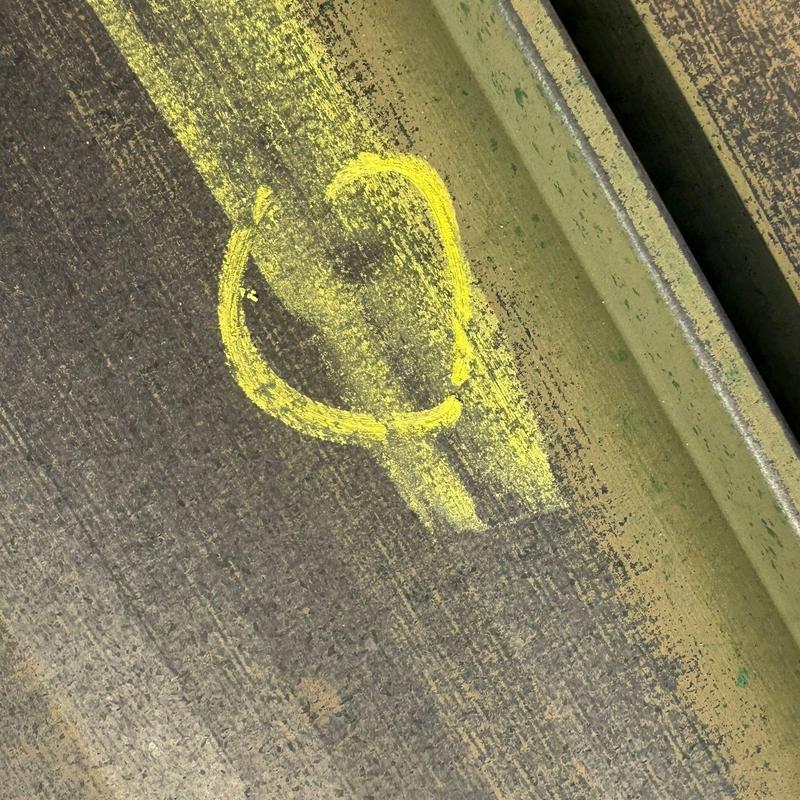 Metal roof panel with hail damage marked in yellow