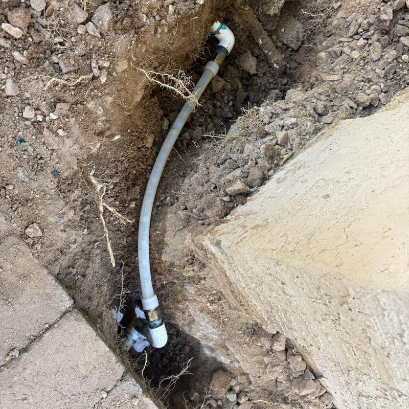 PVC water supply pipe with elbow fitting in trench