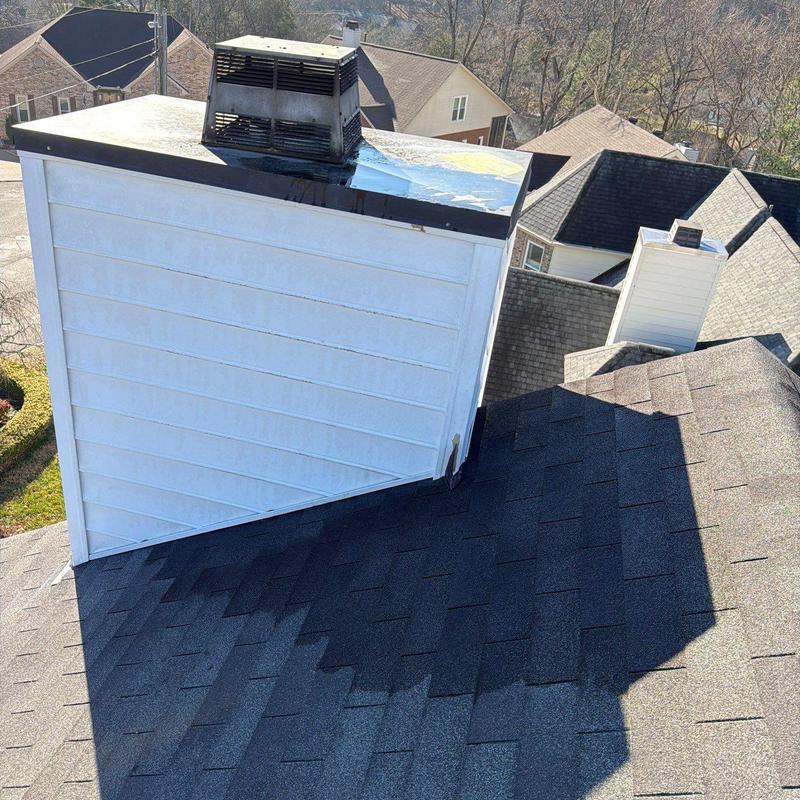 Roof shingles surrounding chimney with hail damage