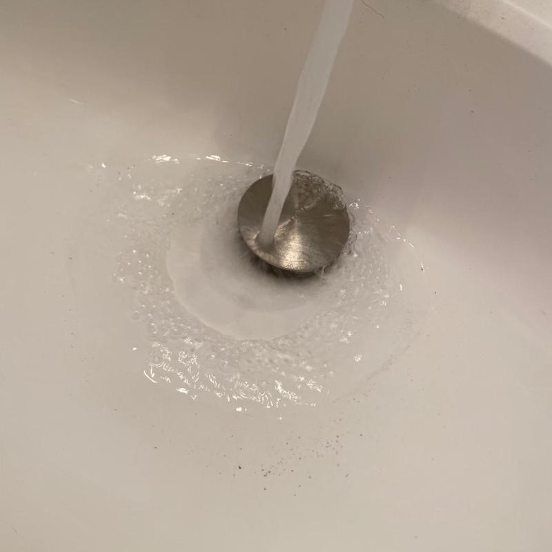 Sink drain with water flow in white basin