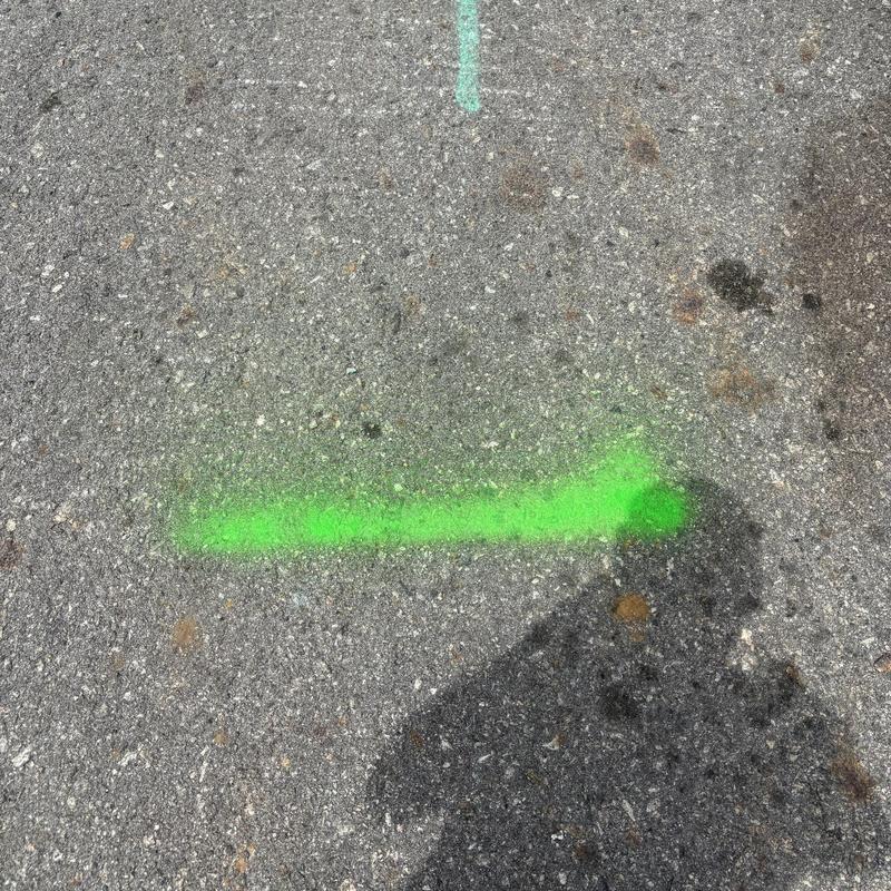 Sewer line location marked on asphalt surface Sewer line location marked on asphalt surface