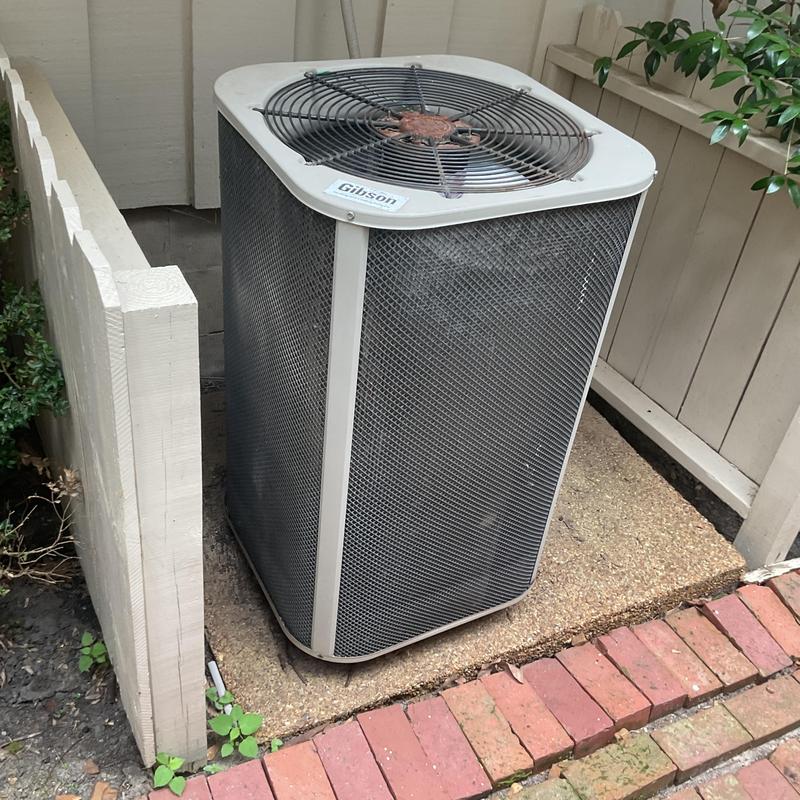 Condenser unit outside home near fence and brick walkway