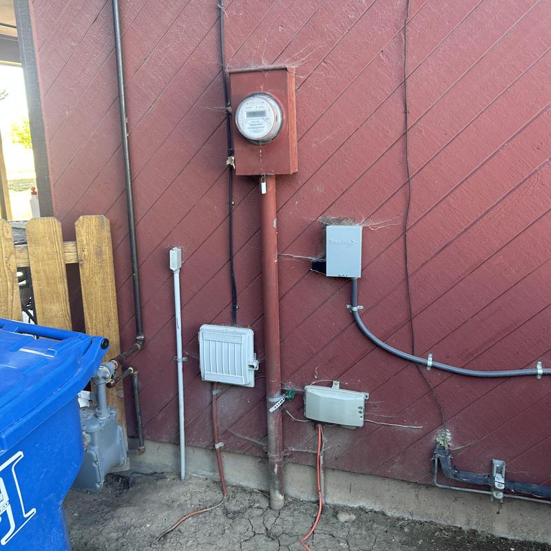 Electrical meter and conduit installation on red exterior wall