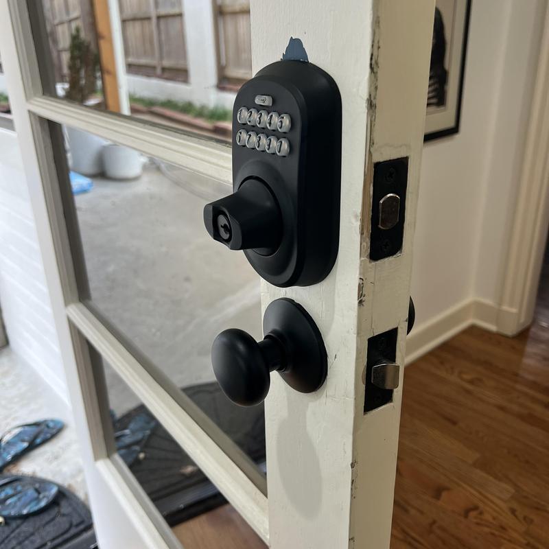 Electronic deadbolt and door knob on white door