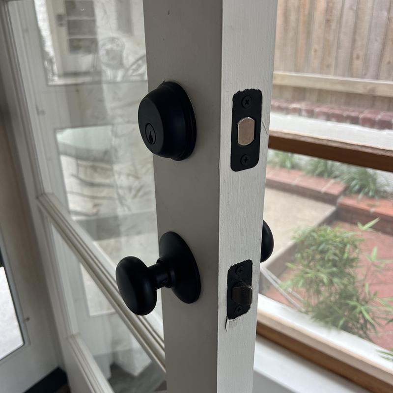 Deadbolts and knobs on white door, black hardware