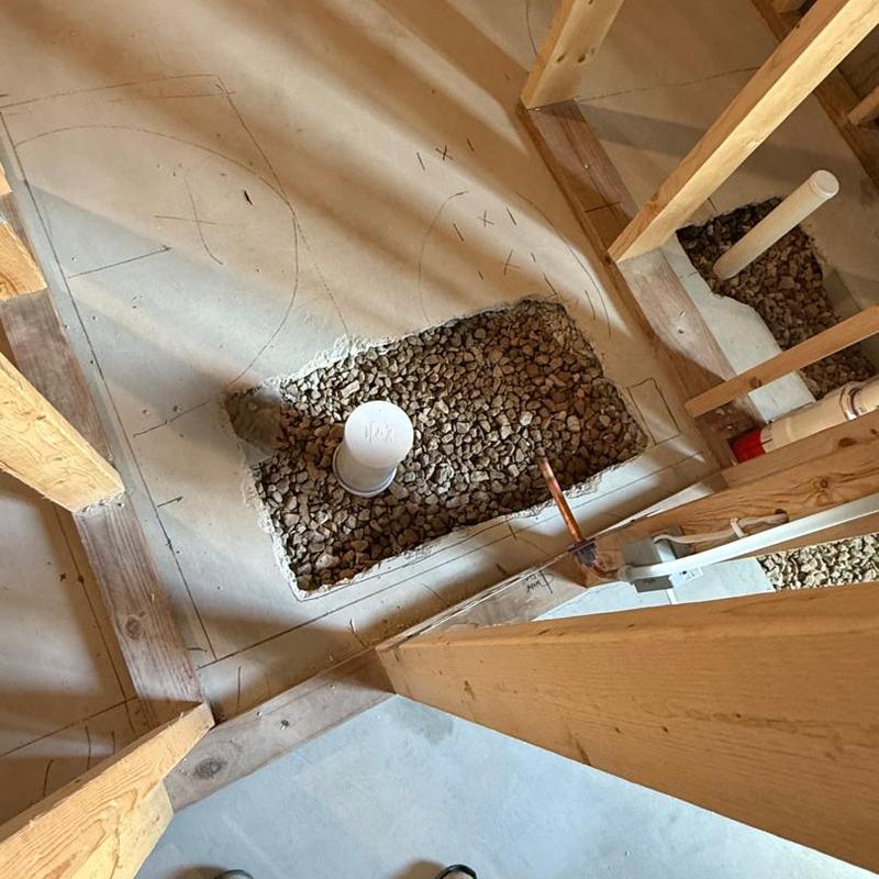 Basement plumbing rough-in with drain pipes and gravel
