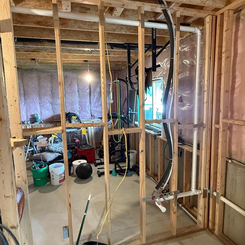 Basement plumbing rough-in with PVC pipes and framing