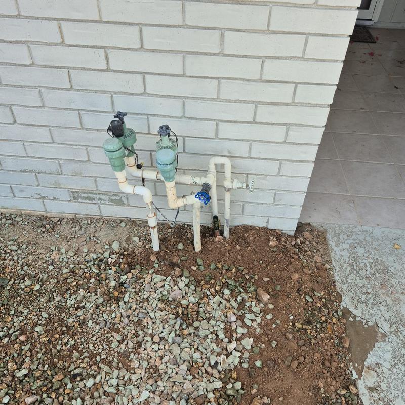 Main water service pipe and valves against brick wall