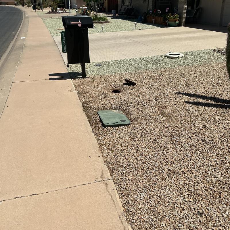 Main water service box and mailbox on gravel yard