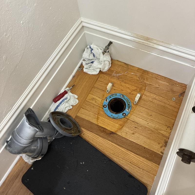 Toilet flange reset with plumbing tools and towel nearby