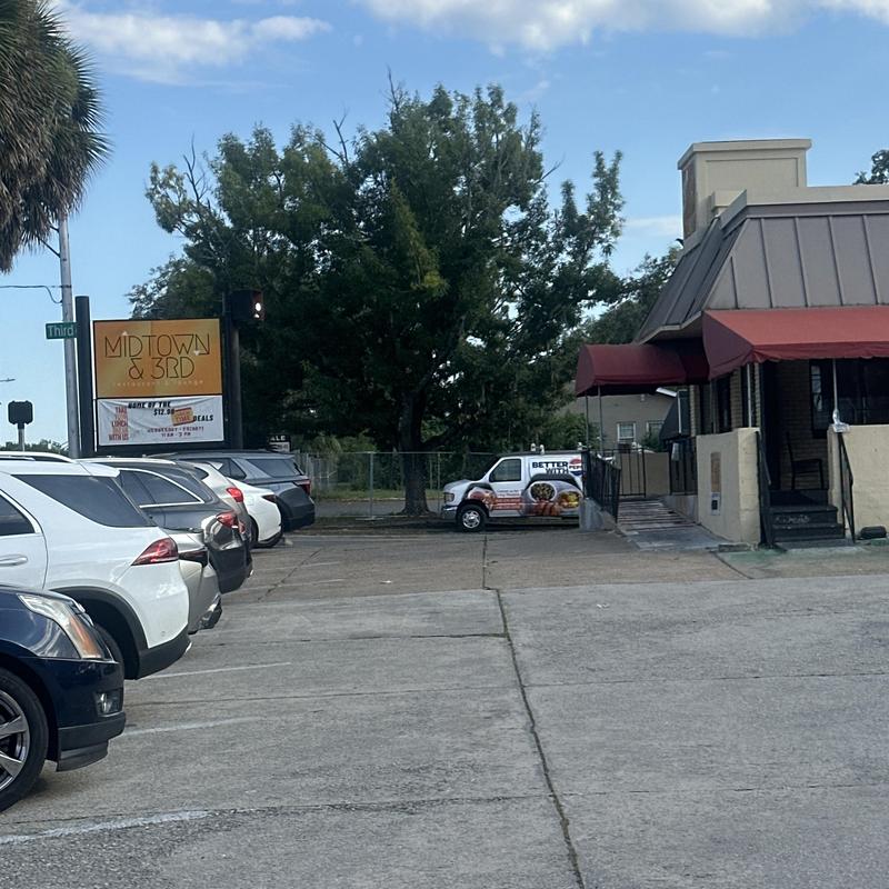 Parking lot with multiple parked vehicles near Midtown & 3rd sign Parking lot with multiple parked vehicles near Midtown & 3rd sign