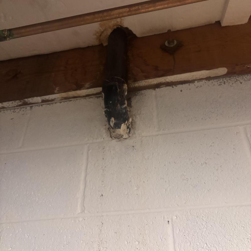 Laundry drain pipe with corrosion damage on wall