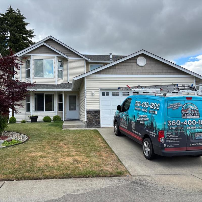 Asphalt shingle roof on two-story home with roofing van Asphalt shingle roof on two-story home with roofing van