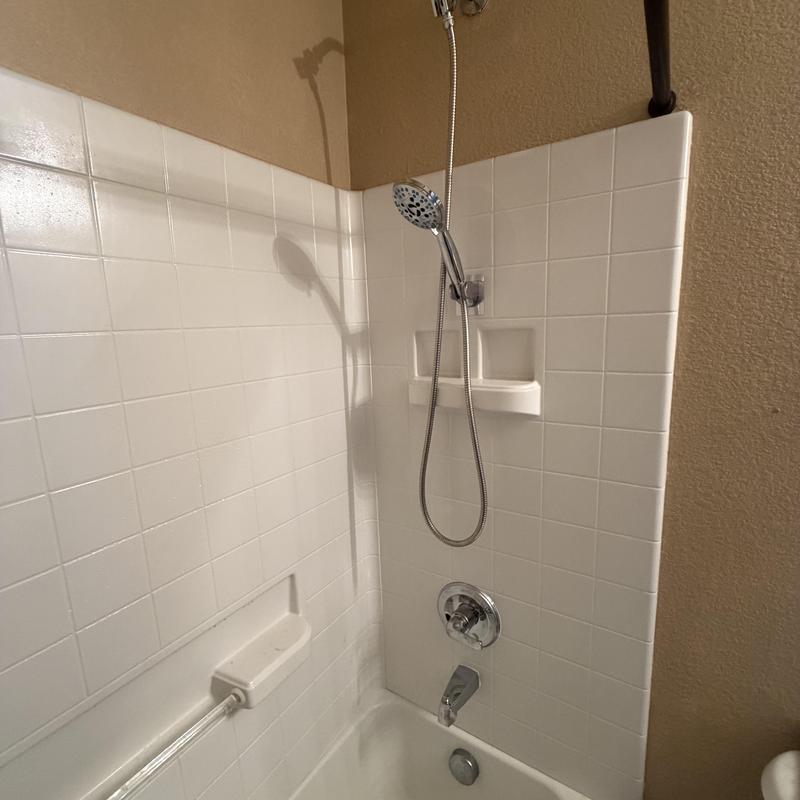 Shower valve and handheld showerhead in white tile tub Shower valve and handheld showerhead in white tile tub