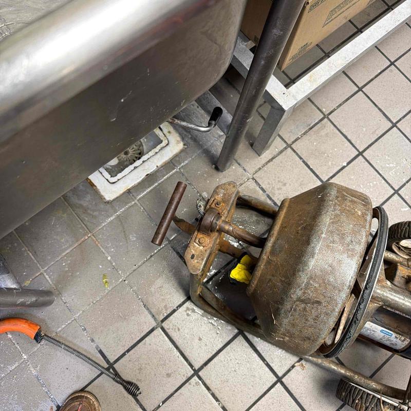 Floor drain with plumber’s drain snake and tools Floor drain with plumber’s drain snake and tools