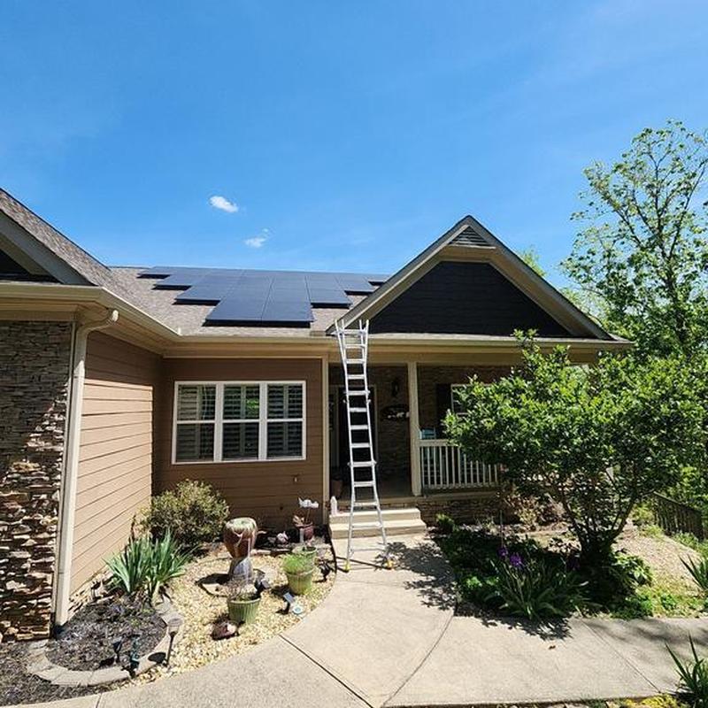 Solar panels on roof with ladder and landscaped yard