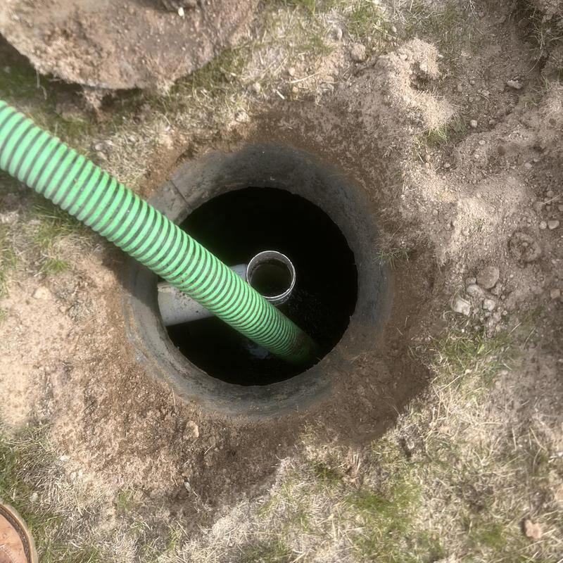 Septic tank with green pump hose during inspection Septic tank with green pump hose during inspection