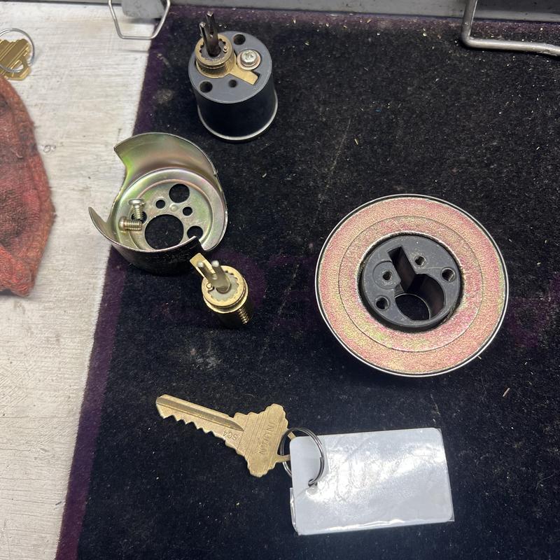 Deadbolt lock parts with rekeyed key on mat
