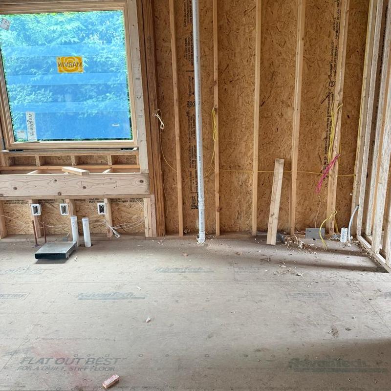 Plumbing rough-in with pipes and electrical outlets in wall framing
