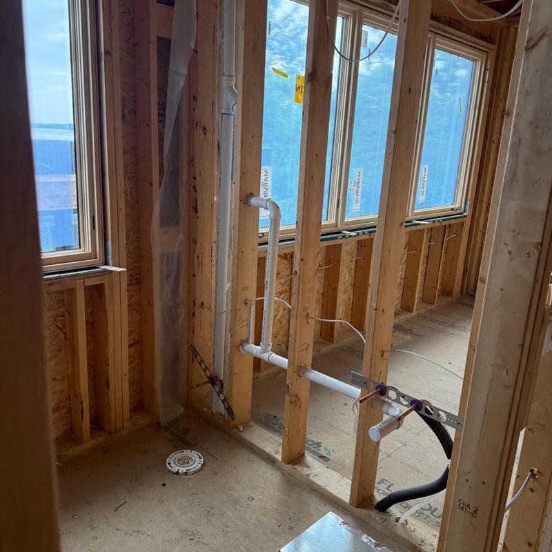 PVC plumbing rough-in with wall framing and windows