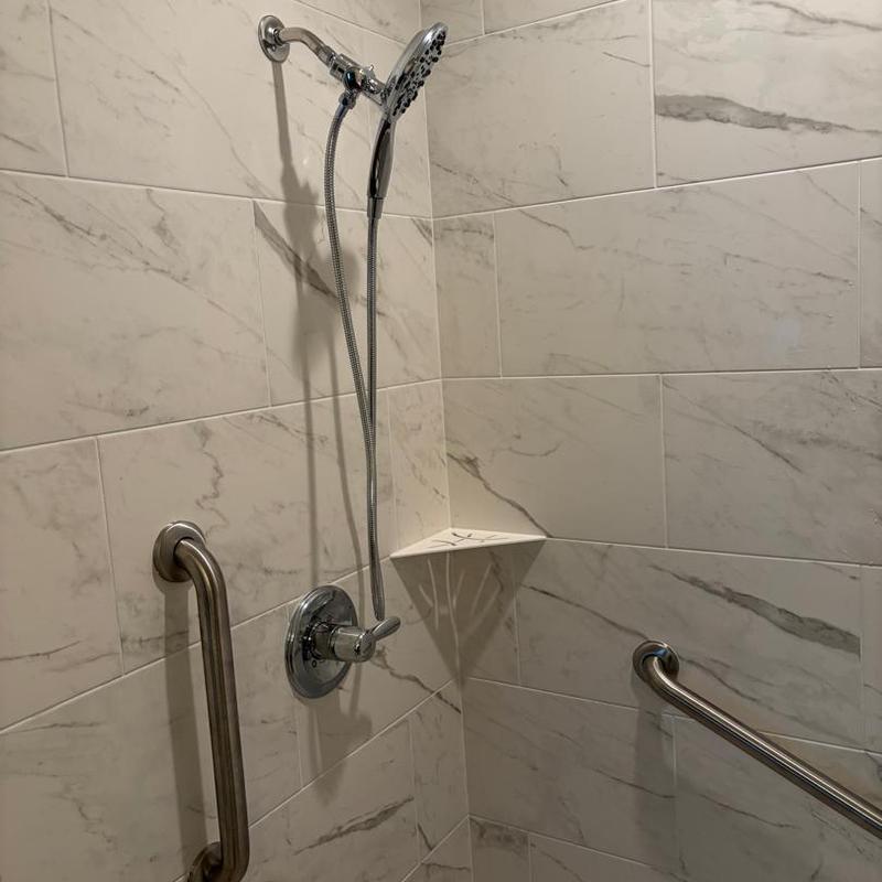 Showerhead and grab bars in tiled shower corner