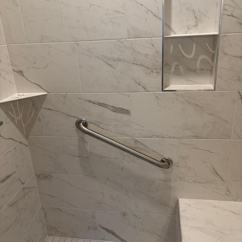 Bathroom safety grab bar installation on marble tile wall