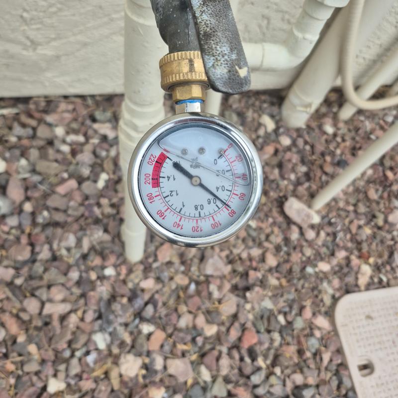 Pressure gauge on outdoor water pipe with gravel background