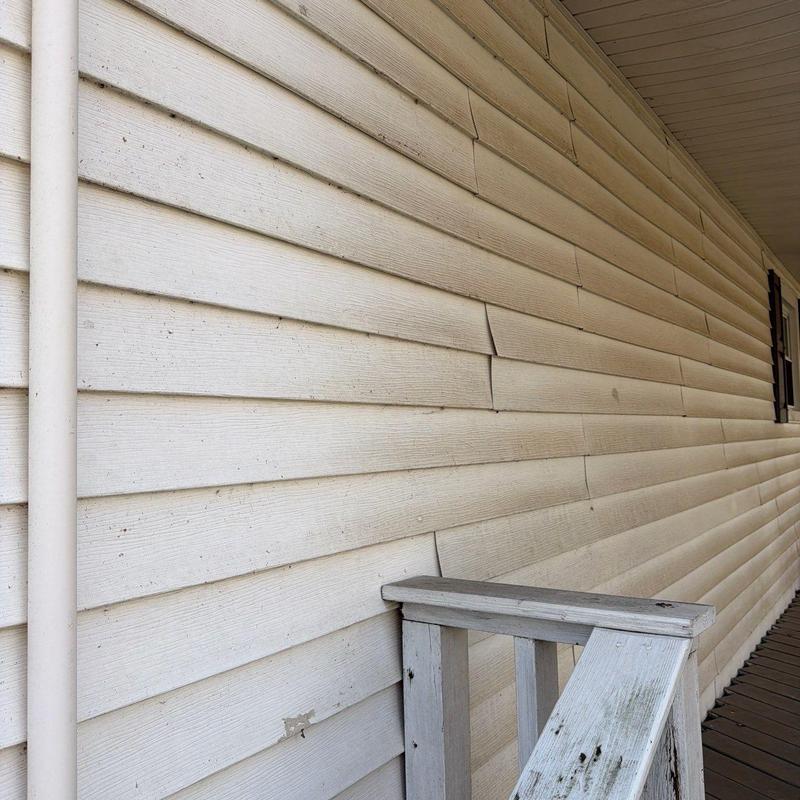 Vinyl siding with warping and damage on porch exterior