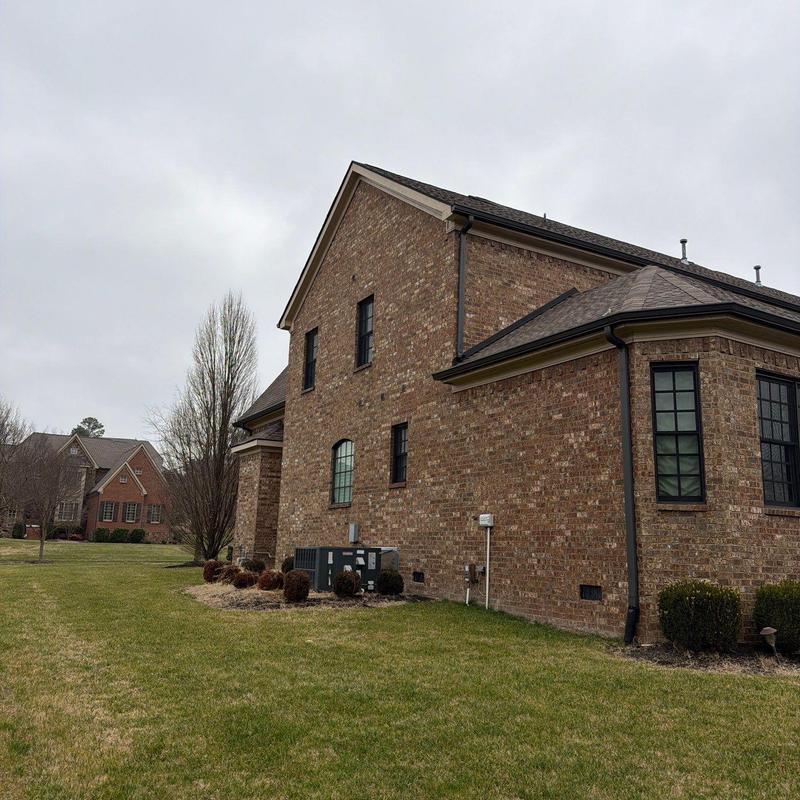 Roof shingles with hail damage on brick home exterior