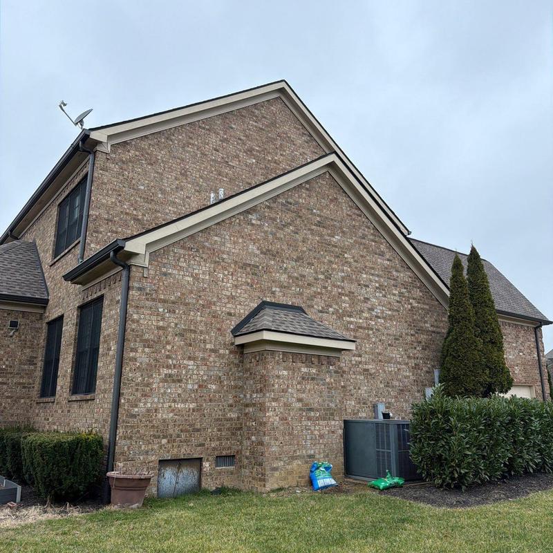 Roof shingles with hail damage on brick home exterior