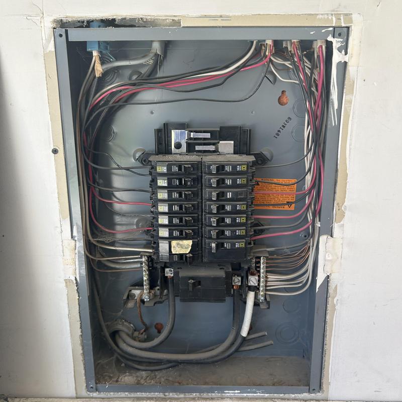 Main electrical panel with exposed wiring and breakers
