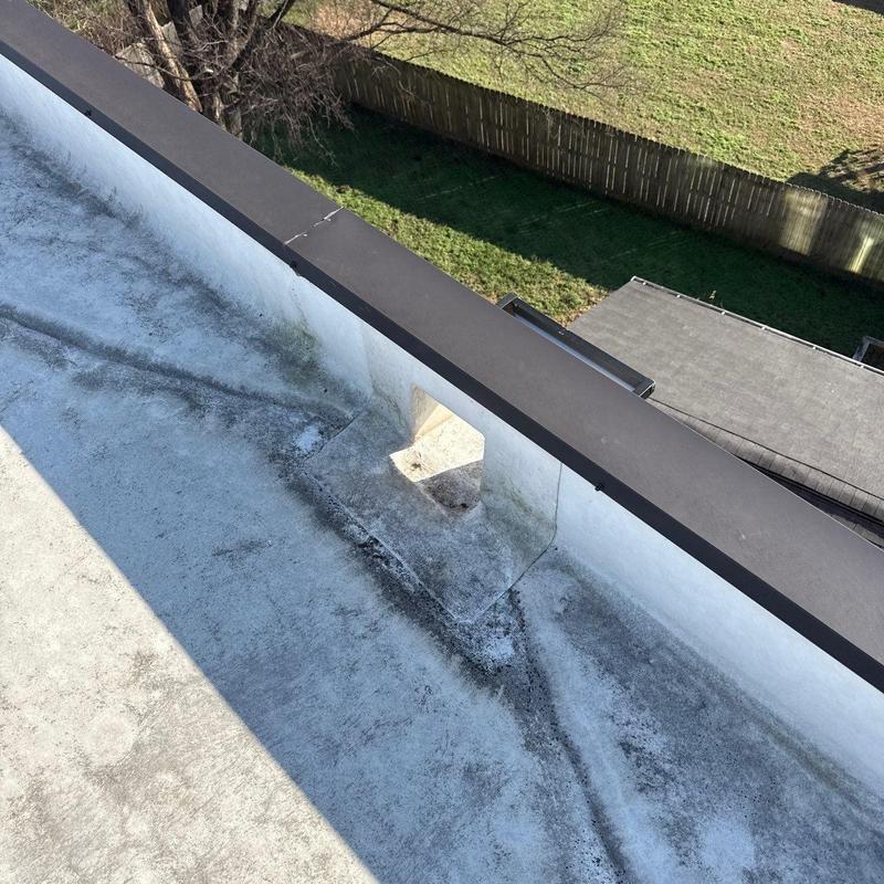 Flat roof drainage scupper on rooftop with debris buildup