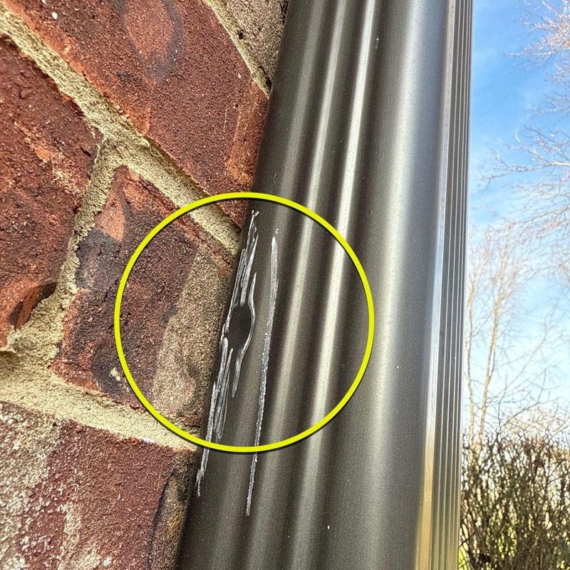 Metal downspout with hail damage dent and scrape