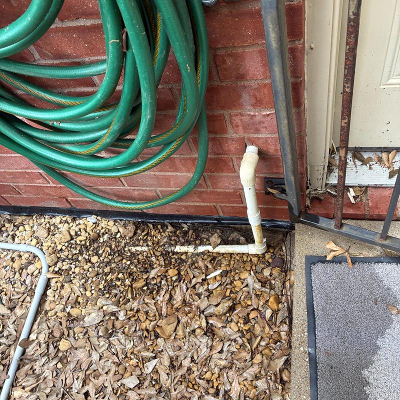 Water system off valve with hose and brick wall